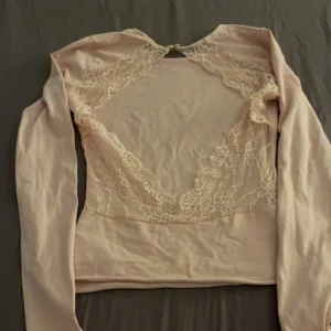 Ljusrosa topp med spetsdetaljer från Gina Tricot - Säljer en ljusrosa långärmad topp från Gina Tricot i storlek XS. Toppen har vackra spetsdetaljer och en öppen rygg med spetskant. Perfekt för dig som gillar feminina detaljer och en elegant look.💕💕
