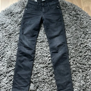 Svarta Replay Anbass jeans - Säljer ett par svarta Replay Anbass jeans med klassisk femficksdesign och dragkedjegylf. Jeansen har en slim passform och är tillverkade i stretchigt material för extra komfort. Perfekta för dig som gillar en stilren look. Amvänd MAX 10-15 gånger