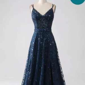 Marinblå glittrig balklänning - Säljer min marinblå balklänning med glittriga detaljer och smala axelband. Klänningen har v-ringning och markerad midja, samt ett lätt utställt fall. Perfekt för balen. Klänningen är inköpt under bal säsongen 2024 från zapaka för ca 1600