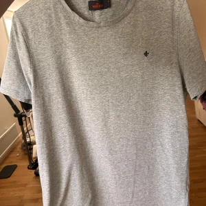 Ljusgrå t-shirt från Morris - Säljer en stilren ljusgrå t-shirt från Morris i storlek M. T-shirten har rund halsringning och en liten broderad logga på bröstet. Perfekt basplagg till garderoben! Helt ny utan prislapp, oanvänd. Ny pris 700 kr, pris kan diskuteras 