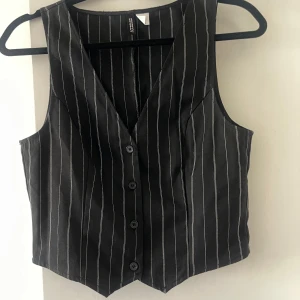 Kostymväst  - Trendig marinblå kostymtopp / kostymväst med vita ränder från HM. V-ringad modell som sitter tajt och har en klassisk, stilren look. Passar perfekt till våren både till vardags och fest. Endast använd en gång så mycket bra skick!