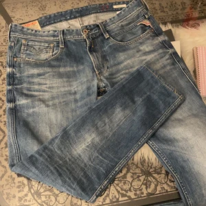 Replay Anbass jeans i ljusblå denim - Säljer ett par Replay Anbass jeans i ljusblå tvätt med klassisk femficksdesign och snygga slitningar. Jeansen har normal passform och raka ben, med Replay-logga vid fickan och broderad detalj bak.