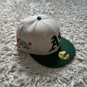 NEW ERA A’S FLATBRIM- VIT, GRÖN - 7 1/8, helt ny aldrig använd, lapparna på kepsen är kvar, perfekt för sommaren, hör av er vid minsta intresse!