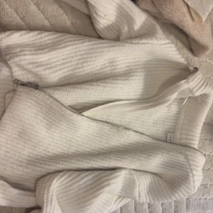 Vit stickad kofta från Vailent - Mysig vit stickad kofta från Vailent i storlek XS. Tröjan har en grovstickad struktur och dragkedja framtill. Perfekt för lager-på-lager och enkel att matcha med olika outfits.