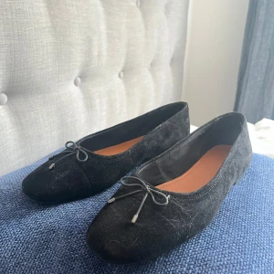 Svarta ballerinaskor från Vagabond - ⚠️pris kan diskuteras vid snabb affär⚠️Säljer ett par klassiska svarta ballerinaskor från Vagabond med rosett framtill. Skorna har rund tå och är tillverkade i mocka med innersula i brunt läder. Säljer för de är precis försmå, de är storlek 37 men brukar ha 38,5/39 så det är lite stora i storleken så tror de passar folk som brukar ha 38. Använda en gång på begravning. De är impregnerade sen innan. Orginalpris 1000kr