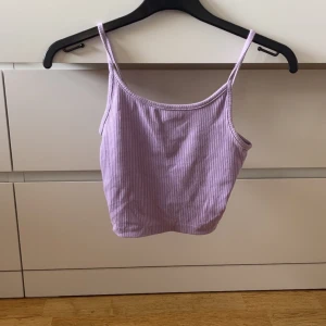 Ljuslila ribbad linnetopp från Sister - Säljer en ljuslila ribbad linnetopp från New Yorker i storlek XXS. Toppen har smala axelband och är croppad, perfekt för varma dagar eller som lager under en skjorta. Supermjuk och stretchig i materialet.