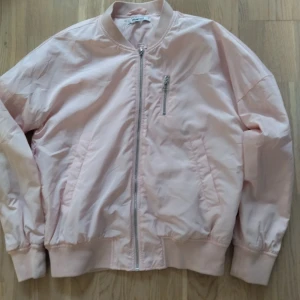 Ljusrosa bomberjacka från Gina Tricot - Säljer en snygg ljusrosa bomberjacka från Gina Tricot. Jackan har en dragkedja framtill och en liten ficka med dragkedja på bröstet. Perfekt för vår och sommar!