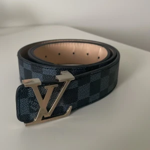 Svart bälte med bronz emblem - Svart bälte med brons emblem. Storlek 120/115 det finns tecken på användning men det är bara på insidan men annars ser bra ut