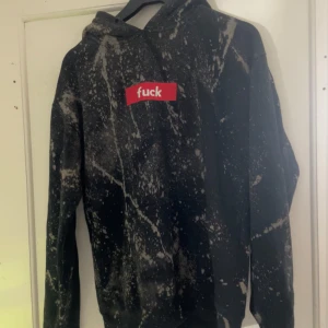 Svart och vit hoodie från FSBN - Cool svart och vit mönstrad hoodie från FSBN med textdetalj på bröstet. Perfekt för en avslappnad stil med en edgy touch. Hoodien har långa ärmar och en klassisk huva.