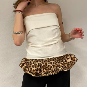 SPOTTED 003 - Stilren handsydd vit tubtopp med en cool leopardmönstrad volangdetalj längst ner. Gjord av handplockad återvunnet material. Skriv gärna byst- och midjemått för att få den skräddarsydd efter just dig🐆💕