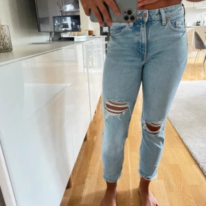 Ljusa jeans med slitningar - Snygga ljusblå jeans med slitningar på knäna. De har en klassisk femficksdesign och är perfekta för en avslappnad stil. Jeansen har en knappgylf och är i en bekväm passform.