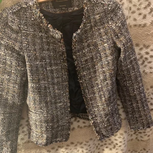 Tweedjacka från Massimo Dutti - Snygg tweedjacka från Massimo Dutti i en mix av svart, vit och beige. Jackan har en klassisk design med långärmade ärmar och en öppen front utan knappar. Perfekt för en stilren look! Säljs för att den är lite tight på mig) kontakta gärna för fler bilder! Pris kan diskuteras!❤️