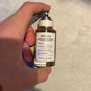 Parfym 'By the Fireplace' från Maison Margiela - Säljer en flaska 'By the Fireplace' från Maison Margiela. Parfymen har en varm och rökig doft med inslag av trä och kastanj. Flaskan är genomskinlig med en enkel och stilren design, och har en metallisk spraytopp. Denna är knappt använd och kan gå ner i pris!