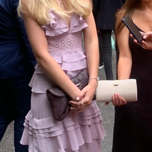 Ljuslila klänning med volanger - Elegant ljuslila klänning med volanger och spetsdetaljer. Klänningen har en omlott-design och är ärmlös, vilket ger en romantisk känsla. Perfekt för sommarens festligheter.