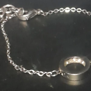 Edblad Silverfärgat armband med cirkelberlock - Edblad Elegant silverfärgat armband med en enkel cirkelberlock. Armbandet är 19 cm långt och har en smidig karbinhake för enkel på- och avtagning. Perfekt för att ge en stilren touch till din outfit.
