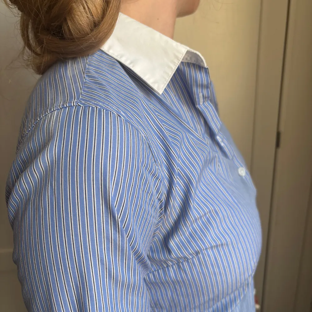 Snygg blå och vit randig bomullsskjorta med långa ärmar och knappar framtill. Skjortan har en klassisk vit krage som ger en stilren look. Perfekt för en chic och avslappnad stil. . Paidat.