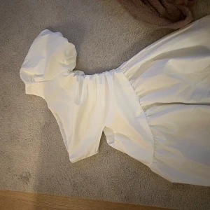 Vit klänning med puffärm - Säljer en söt vit klänning med puffiga kortärmar och en elegant design. Perfekt för sommarens alla tillfällen. Klänningen har en smickrande passform och är gjord i ett lätt och bekvämt material. 