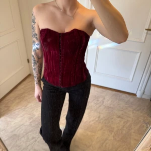 Vinröd korsett & kavaj från Joelle by Ellos - Vinröd korsett och matchande kavaj i sammet. Korsetten har en elegant snörning i ryggen vilket gör att man kan justera storleken. (Jag har S) Säljer korsetten och kavajen tillsammans!❤️