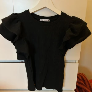 Söt topp från Zara - Jättefin topp med volang på axlarna i storlek S, väldigt bra och rejält material och snygg passform. Inte så kort utan bra längd och fin urringning, använd 4 gånger och köptes för några år sedan