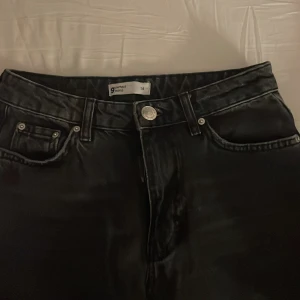 Svarta jeans från Gina tricot  - Snygga svarta jeans från Gina tricot med klassisk femficksdesign och knappgylf. Perfekta för en stilren look.