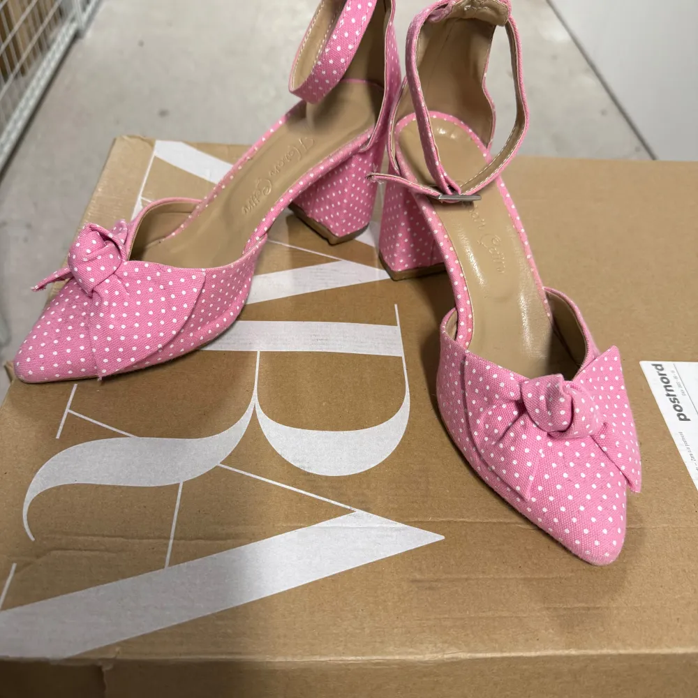 Snygga rosa klackskor med vita prickar och en charmig rosett framtill. Skorna har en spetsig tå och en bekväm klack. Perfekta för att lägga till en färgglad touch till din outfit.. Kengät.