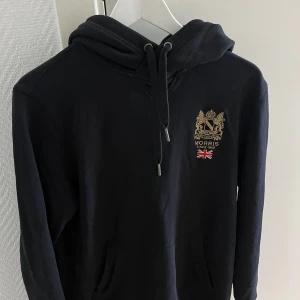 Svart hoodie från Morris - Säljer en stilren svart hoodie från Morris ✅. Perfekt för en avslappnad stil. ✅ köpt för 1,499kr.  ✅ Storlek Medium ✅ Mitt pris är 699kr ✅ Pris kan eventuellt diskuteras! 👏✅