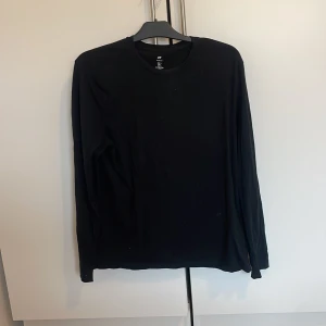 Svart långärmad tröja från H&M - Säljer en stilren svart långärmad tröja från H&M i slim fit. Perfekt för en minimalistisk look. Tröjan är tillverkad i ett mjukt material som ger en bekväm passform.