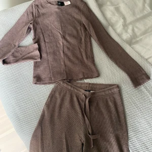 Brunt mjukisset från H&M - Säljer ett brunt ribbat mjukisset från H&M med långärmad tröja och vida byxor. Perfekt för en avslappnad stil. Tröjan har en rund halsringning och settet är i ett mjukt material.