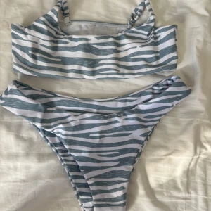 Zebramönstrad bikini - Snygg bikini med zebramönster i grått och vitt. Överdelen har en rak skärning och smala axelband. Perfekt för en dag på stranden eller vid poolen. Ny skick Stl xs