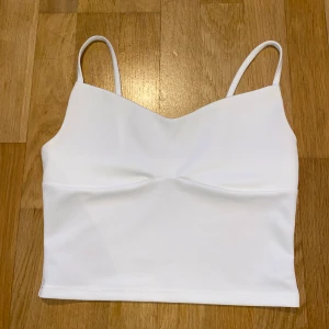 Vit ärmlös linnetopp - Snygg vit ärmlös linnetopp med smala axelband. Perfekt för varma dagar eller som ett basplagg i garderoben.