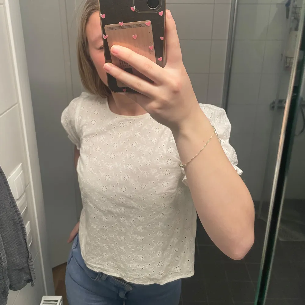 Säljer en söt vit blus med spetsdetaljer och korta puffärmar. Perfekt för en somrig look. Blusen har en rund halsringning och en knapp i ryggen för enkel påklädning. Passar bra till både jeans och kjol! Går att pruta. Liten ljusgul fläck som man knappt ser som ni ser på bilderna. Står ingen storlek men skulle säga s. Köpt här på Plick så vet ej vilket märke det är då det inte står i . Puserot.
