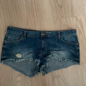Jeansshorts  - Mörkblå jätte fina lågmidjade jeansshorts med slitningar från gina tricot, storlek 42. Formar jätte fint, passar perfekt till sommarn! 💕🙏🏻 midjemått 44, grenhöjd 20!