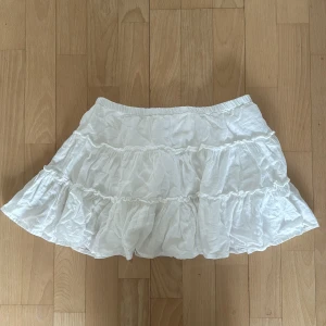 Vit volangkjol, Mini skirt från pull & bear. Storlek S/Xs💗 - Söt vit kortkjol med volanger, perfekt för sommardagar. Kjolen har en elastisk midja för bekväm passform och är gjord i ett lätt material som ger en luftig känsla.💗Bra skick