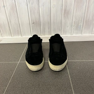 Svarta sneakers från Axel Arigato - Snygga svarta sneakers från Axel Arigato med en stilren design. Skorna har en vit sula och är tillverkade i skinn. Perfekta för en casual look. Två påsar ingår och box. Ifall ni inte vill ha den stora påsen är det okej bara att skriva det. 