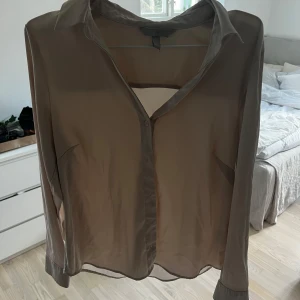 Två silkes skjortor i beige och grå - Säljer två eleganta blusar med långa ärmar och knappar framtill. Perfekt för en stilren look. De ser väldigt genomskinliga ut men inget syns igenom på.