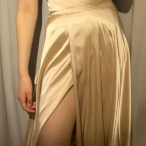 Balklänning  - Champagne färgad Balklänning köpt från Ivory Field på NK. Klänningen är använd endast en gång men är i superbra skick. Original priset är 3300 kr men jag säljer den för 990 kr. Storlek 32-34. Jag säljer klänningen för att den inte riktigt är min stil.