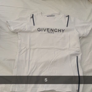  Givenchy t shirt  - Säljer en stilren vit t-shirt från Givenchy med svart text på bröstet. T-shirten har korta ärmar och en normal passform. Perfekt för en avslappnad och trendig look.