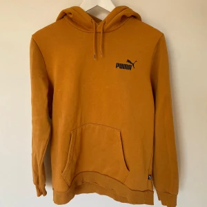 Orange hoodie från Puma - Säljer en snygg orange hoodie från Puma med klassisk logga på bröstet. Tröjan har en bekväm passform med långa ärmar och en praktisk magficka. Perfekt för en avslappnad stil.
