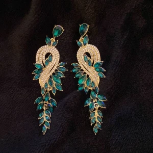 Guld och gröna örhängen med stenar - Eleganta örhängen i guld med gröna stenar i en böljande design. Perfekta för att ge en lyxig touch till din outfit. De har en unik form med flera små stenar som ger ett glittrande intryck.