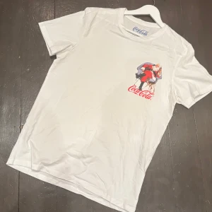  Jack & Jones T-Shirt -  Denna Jack & Jones T-shirt är i samarbete med Coca-Cola, Och har ett tryck på vänster bröst. Tröjan är i toppskick, Och är knappt använd. Den sitter som M. Modellen på bilden är 188 cm lång och väger 70kg. Om du har några frågor är det bara att skriva!   //  T-Arkivet 😊