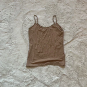 Beige linnetopp - Säljer en stilren beige linnetopp med smala axelband. Perfekt för lager-på-lager eller att bära som den är. Passar till både jeans och kjol.
