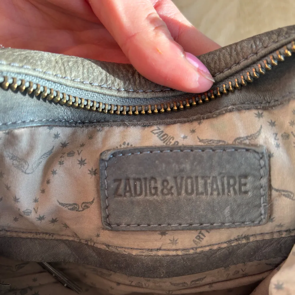 Snygg brun skinnväska från Zadig & Voltaire med praktiska dragkedjor och ett stilrent mönster på insidan. Väskan har både handtag och en justerbar axelrem för flexibel användning. Perfekt för att bära dina dagliga nödvändigheter med stil. OBS❗️❗️Tre små små hål i innertyget(märks ej på något sätt). Laukut & Käsilaukut.