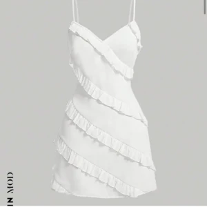 Vit omlottklänning med volanger - Snygg vit omlottklänning med volangdetaljer. Klänningen har smala axelband och en kort längd, perfekt för sommarens varma dagar då den inte är för tjock💗Lapp kvar och säljer då den aldrig kommit till användning! Nypris 239kr. För fler bilder kom privat! Pris kan även diskuteras!