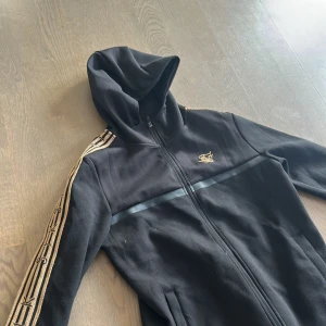 Snygg svart guld hoodie från siksilk - Helt oanvänd hoodie från siksilk. När jag köpte den låg den på 1424kr och säljer den för 499kr priset går att pruta. Hör av er vid frågor!