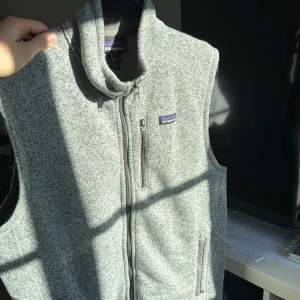 Patagonia fleece väst grå - Hej, säljer nu min gråa Patagonia fleece väst, som jag köpte i april förra året men som tyvärr inte kom till användning då den inte riktigt var min stil. Har använt den så lite som 5 gånger sedan den köptes. Västen är en skön och ganska så varm väst som man kan använda under en jacka när de är väldigt kallt men också en väst man kan använda på en sen sommarkväll. Västen är i storlek Large. Om du har fler frågor så tveka inte att ställa dem. Digitalt kvitto finns! MVH Vincent  