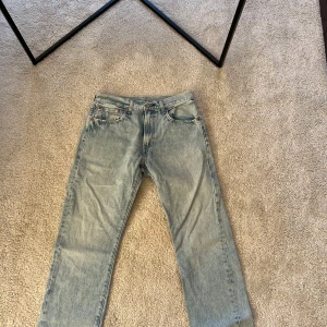 Levi's 551 ljusblå jeans - Säljer ett par klassiska Levi's 551 jeans i ljusblå denim. De har en rak passform och är perfekta för en avslappnad stil. Jeansen har fem fickor och en knappgylf.