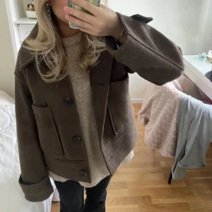 Brun kappa från Kappahl - Inte mina bilder men kan absolut skicka vid intresse! Pris kan diskuteras. Säljer en stilren brun kappa från Kappahl med stora knappar och bred krage. Jackan har långa ärmar och praktiska fickor framtill. Perfekt för kyligare dagar.