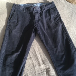 Mörkblå chinos från Gant - Snygga mörkblå chinos från Gant med klassisk design. Byxorna har en knapp och dragkedja framtill samt hällor för bälte. Perfekta för en stilren look.