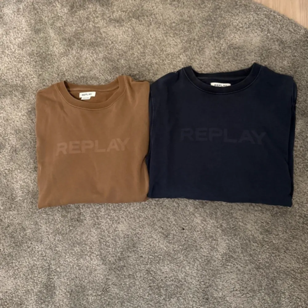 Två stilrena tröjor från Replay i färgerna brun och marinblå. Båda tröjorna har en diskret logotyp på bröstet och rund halsringning. Perfekta för en avslappnad look.. Neuletakit & Villapaidat.