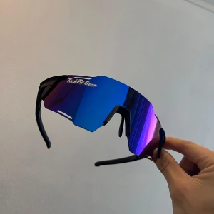 Blå sportglasögon från TechFit Gear - Snygga sportglasögon med spegelblå lins och svart båge från TechFit Gear. Perfekta för utomhusaktiviteter med en modern och futuristisk design.